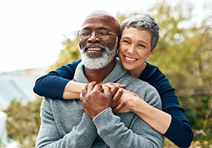 A man and woman smiling with dental implants